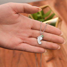 Load image into Gallery viewer, Hand holding silver footprint necklace with birthstone