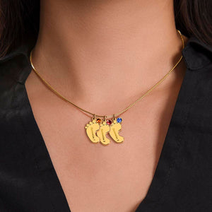 Woman wearing gold 3-footprints necklace with birthstones